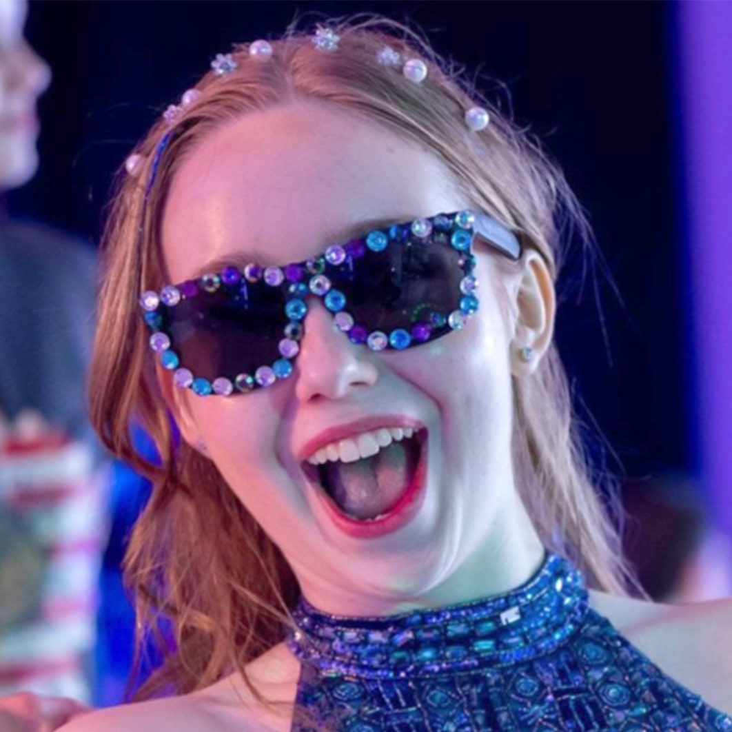 Historia del paciente: Aubri feliz y sonriendo con gafas de sol deslumbradas