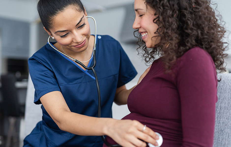Female doctor listens to expectant mom's tummy with stethoscope