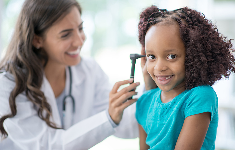 Female doctor uses otoscope on young black girl