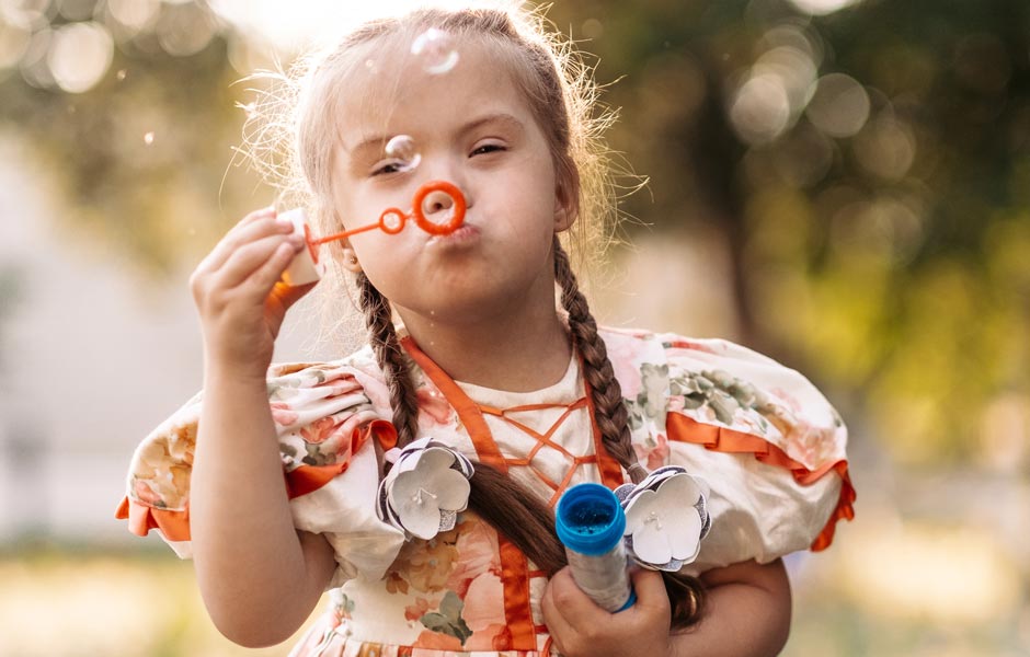 Toddler with Down syndrome blows bubbles. 
