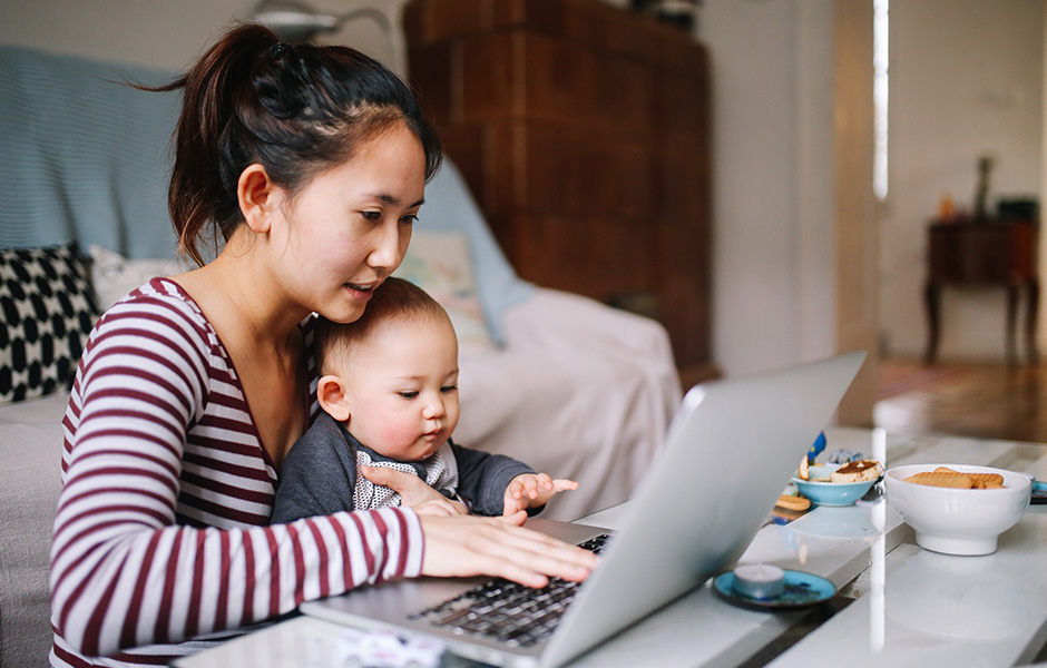 Mother using laptop with infant boy on her lap