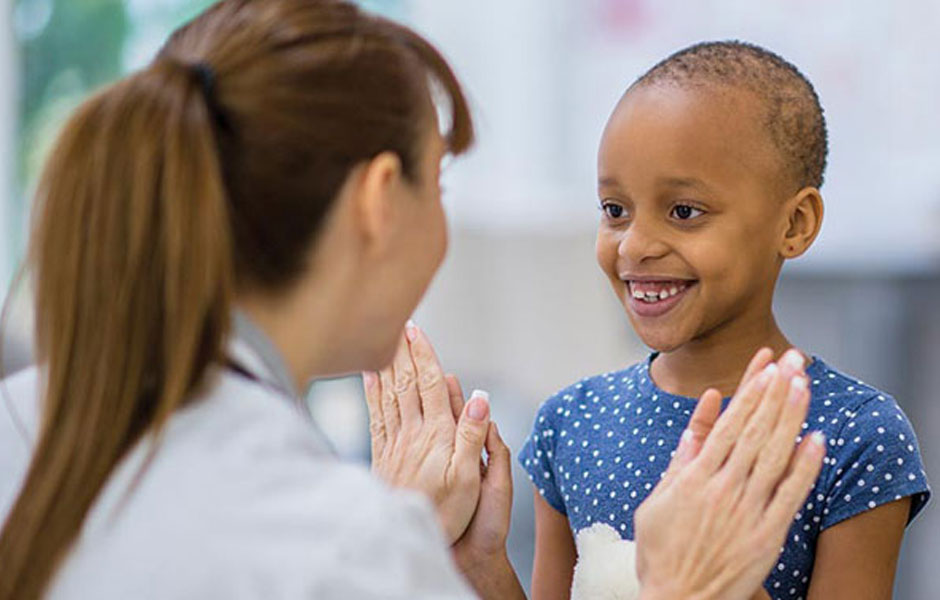 A smiling school-aged patient gives a high-five to a female doctor.