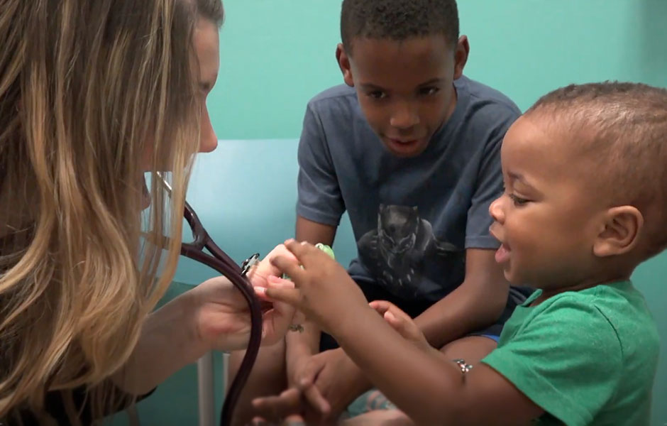 A doctor meeting with two children in a doctors office.