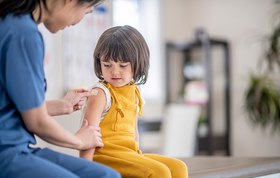 Medical provider placing bandage on the arm of young white girl after getting a shot