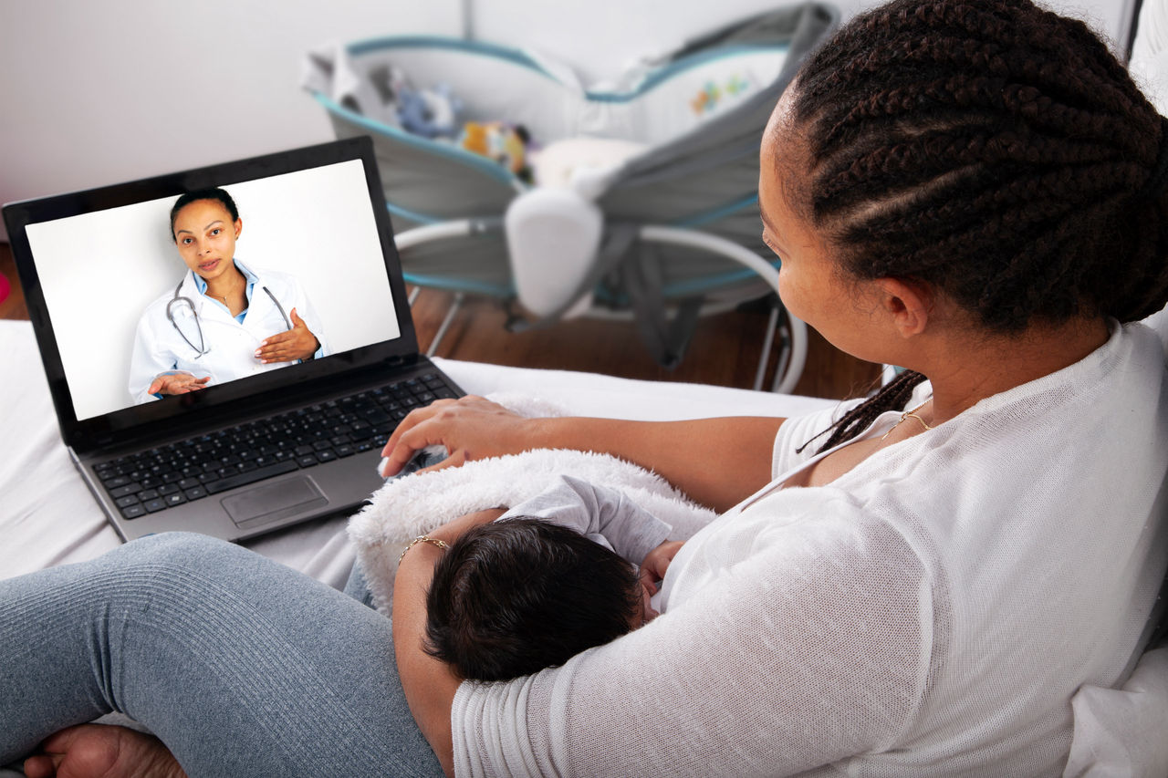 Una madre con su bebé durante consulta virtual con una médica