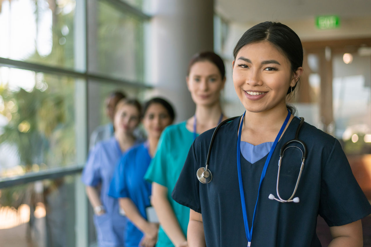 A group of smiling nurses and doctors posing together. 