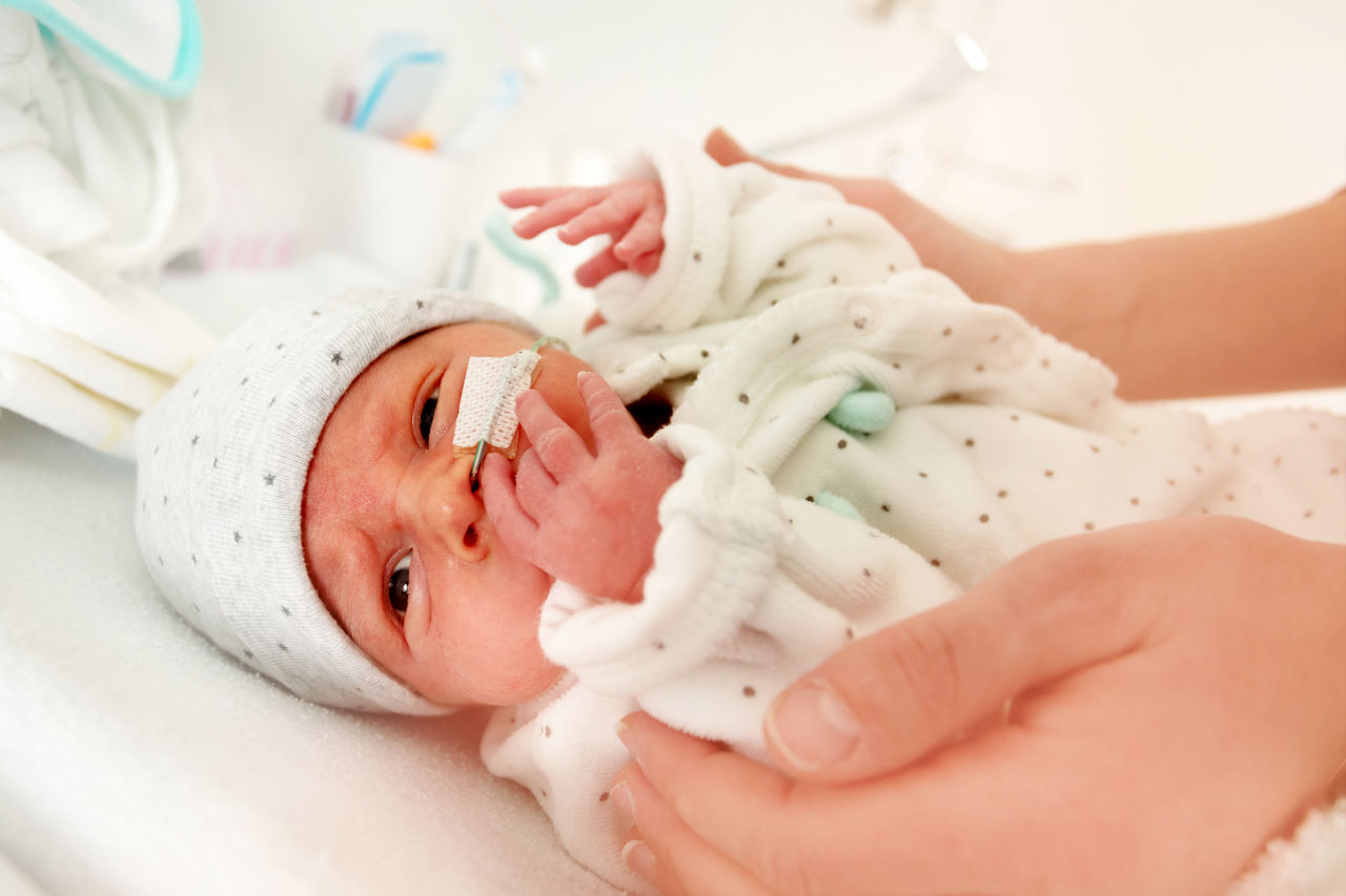 Baby with feeding tube and caregivers hands