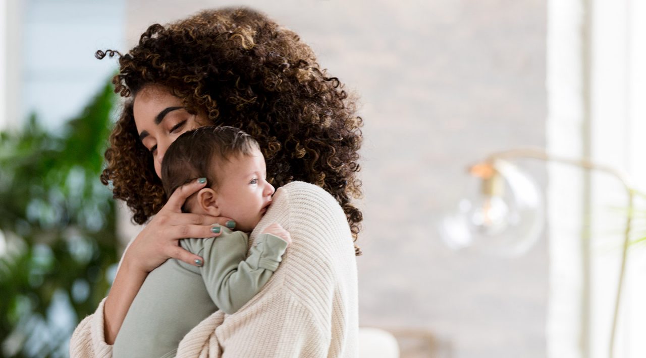 Mom holds baby over her shoulder. 