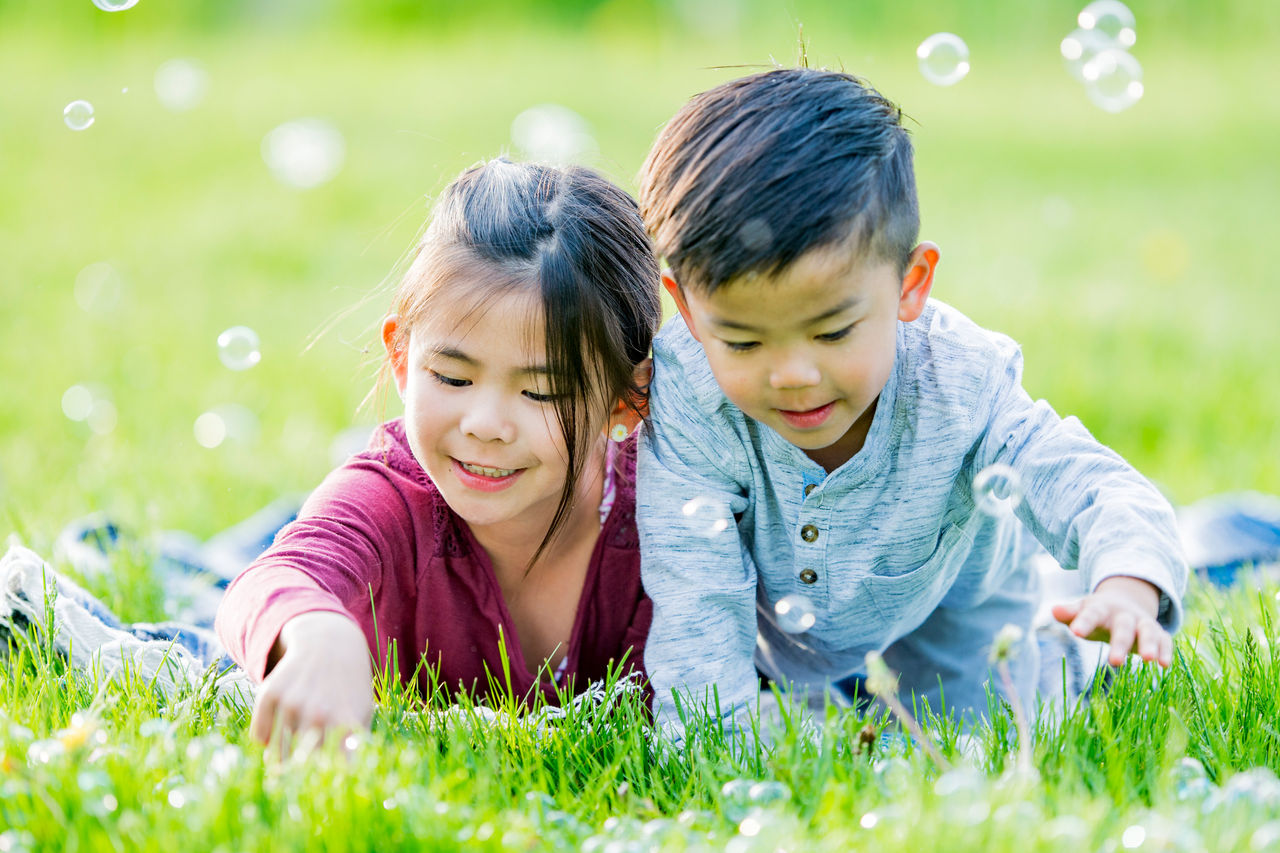 siblings laying in grass with bubbles siblings laying in grass with bubbles