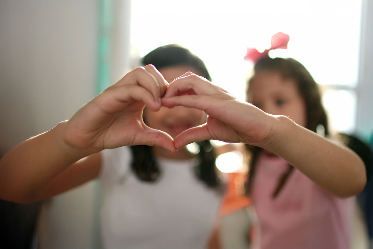 Two children making a heart with their hands. Two children making a heart with their hands.