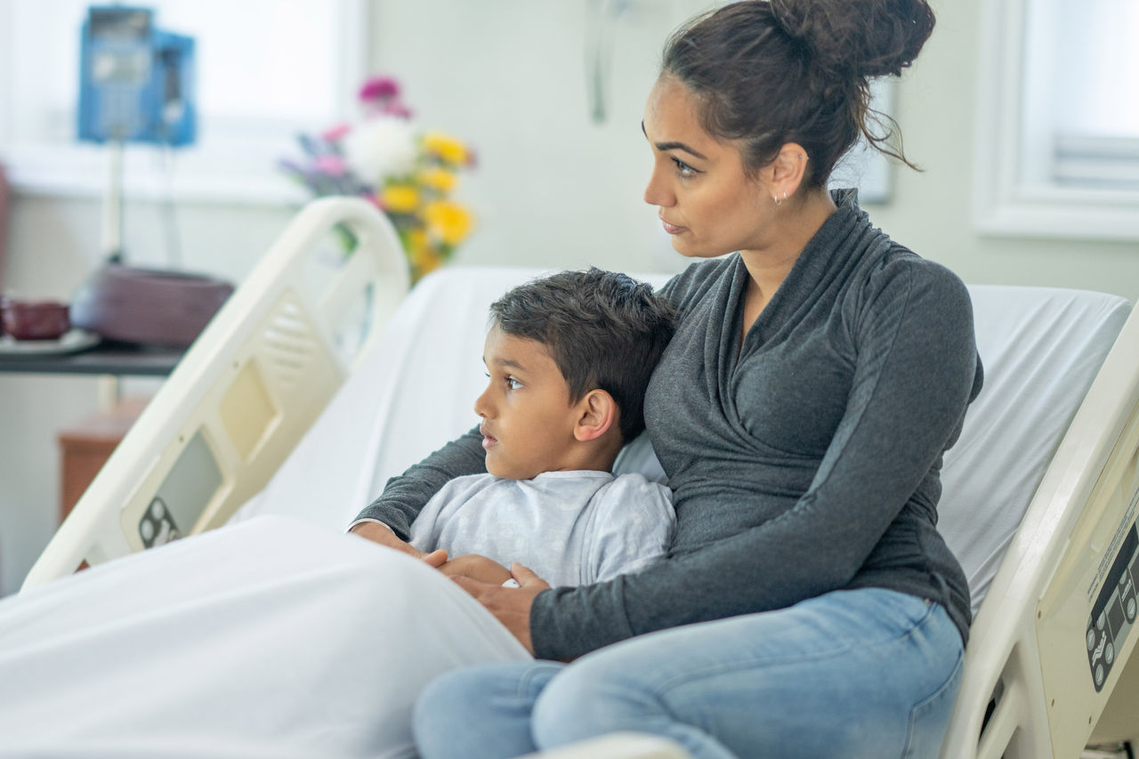Mom comforting son in hospital bed Mom comforting son in hospital bed