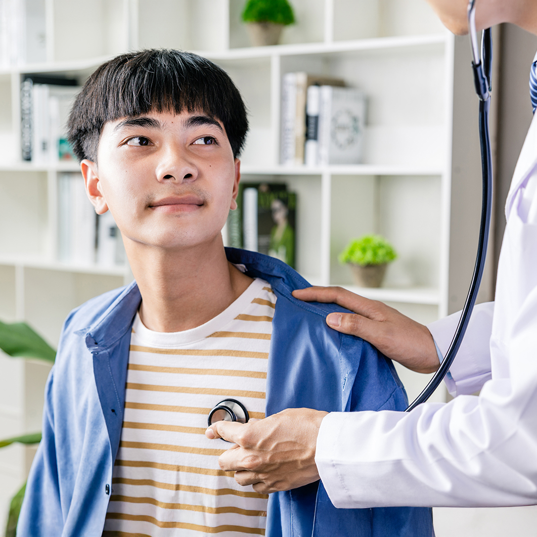 Doctor listening to a male teen's heart with a stethoscope 