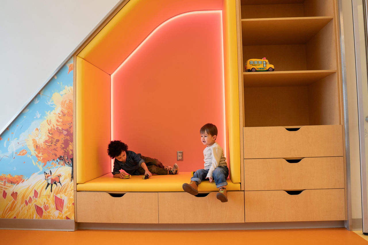 Two boys playing in a book nook built into a wall