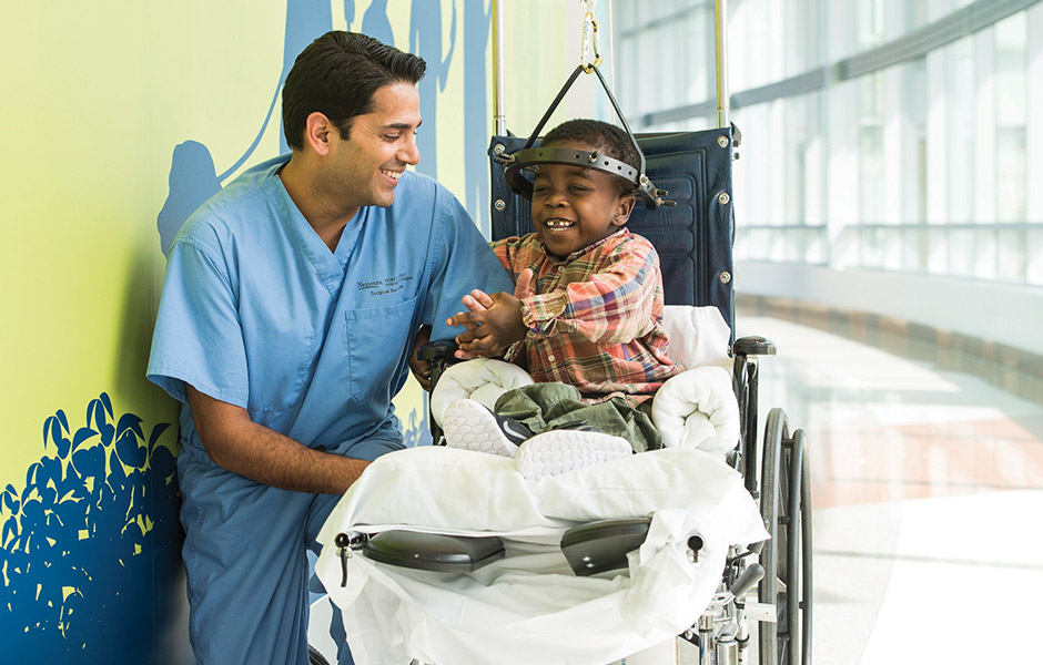 Male patient in the hospital in a wheelchair and wearing a halo brace after having spine surgery, talking with surgeon and smiling