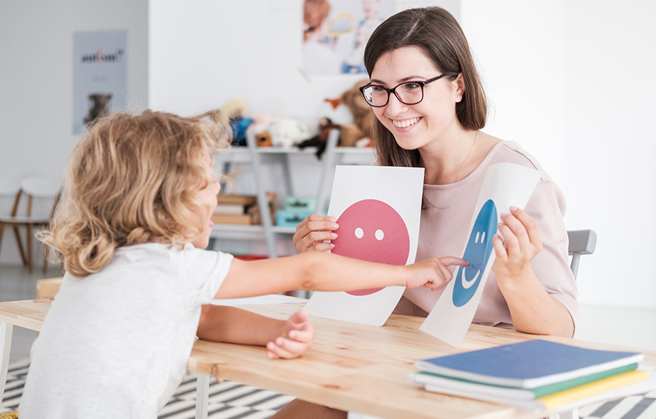 Young professional woman shows emotion drawings to a young child Young professional woman shows emotion drawings to a young child who points to one