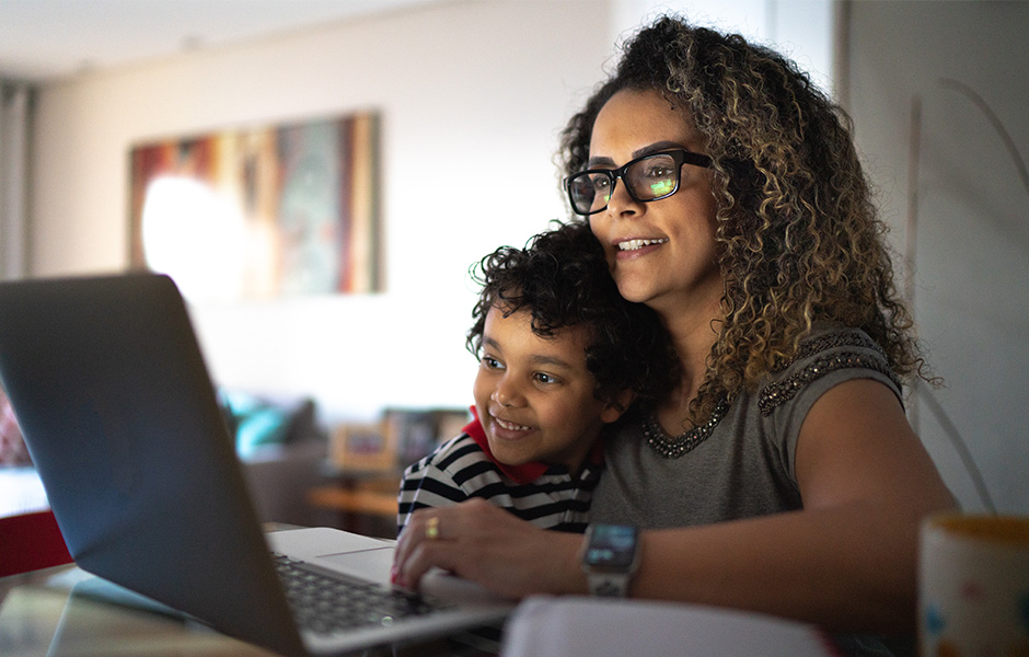 Smiling mom and smiling preschooler look at laptop Close-up of smiling mom and smiling preschooler looking at laptop