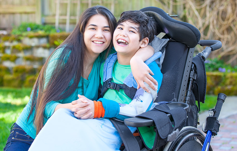 Young boy who uses a wheelchair is hugged by his mom outside 