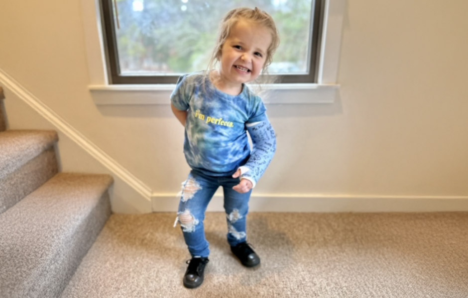 Mackenzie, a young girl with osteogenesis imperfecta standing at the bottom of a staircase