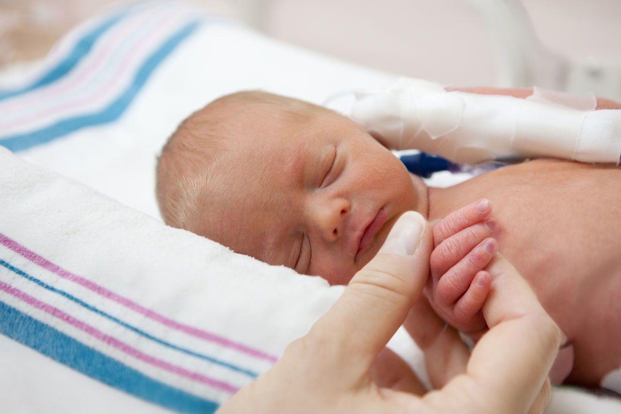 Un bebé que está dormido mientras la madre le sostiene la mano.
