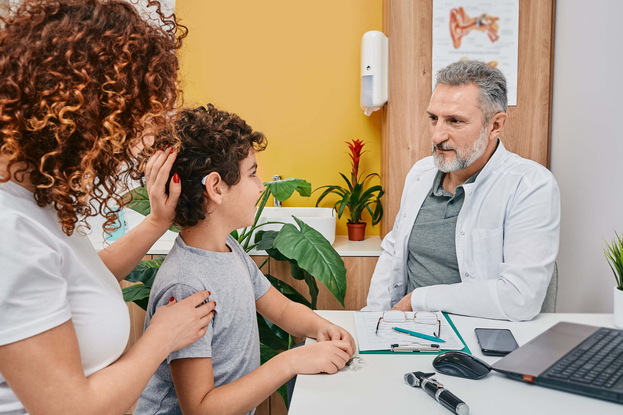 Médico sentado con paciente y madre
