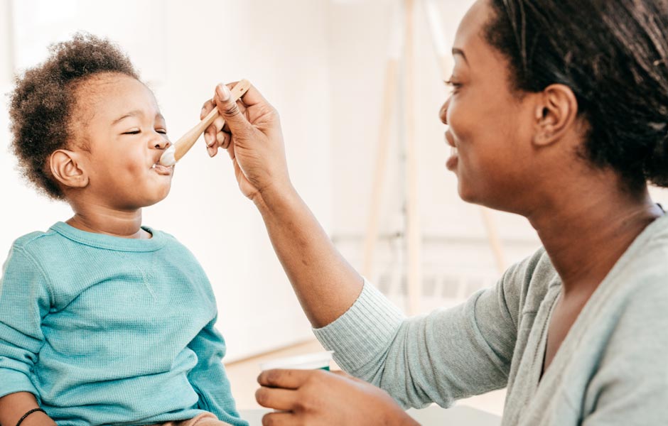 Young mom feeds her toddler with a spoon. Young mom feeds her toddler with a spoon.