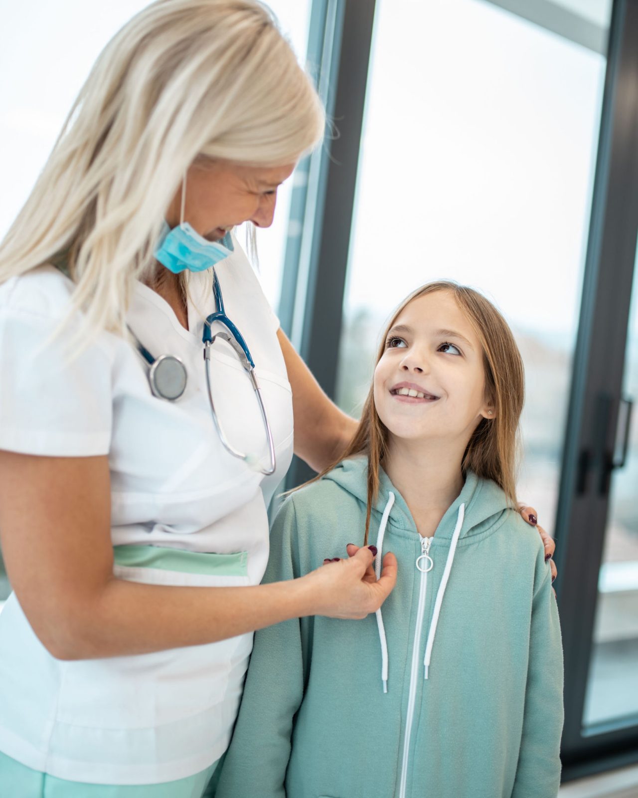 Primer plano de una médica sonriendo y hablando con una niña durante un examen médico en el consultorio del pediatra