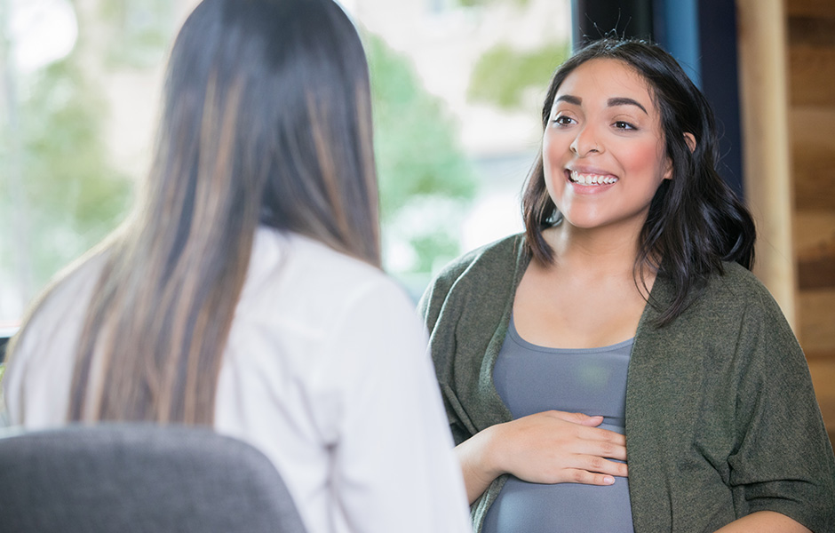 Female doctor in lab coat talks with smiling expectant mother Female doctor in lab coat talks with smiling expectant mother