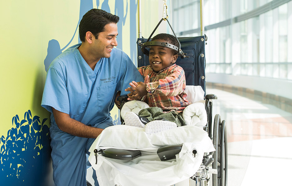 Male patient in the hospital in a wheelchair and wearing halo talking with Dr. Shaw, Male patient in the hospital in a wheelchair and wearing halo ta Male patient in the hospital in a wheelchair and wearing a halo brace after having spine surgery, talking with surgeon and smiling