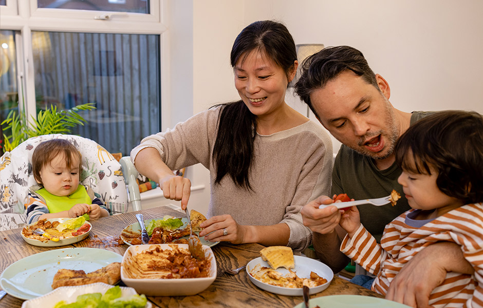 Diverse family spending time together in their home around a dining table in the north east of England. They are enjoying a family meal together and catching up as a family over dinner.