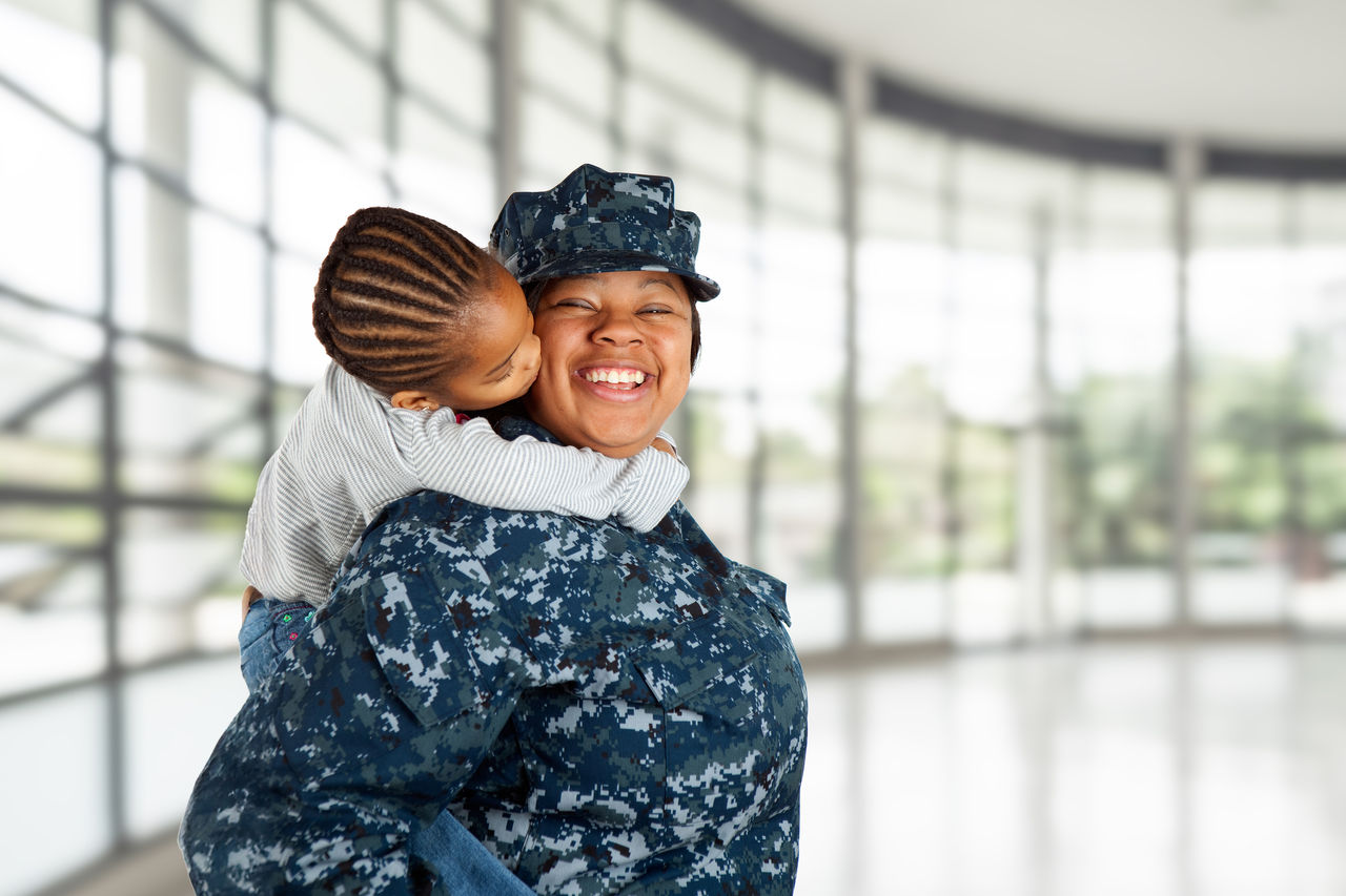 Mother wearing a military uniform gets a kiss from her child