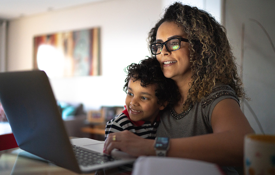 Close-up of smiling mom and smiling preschooler looking at laptop