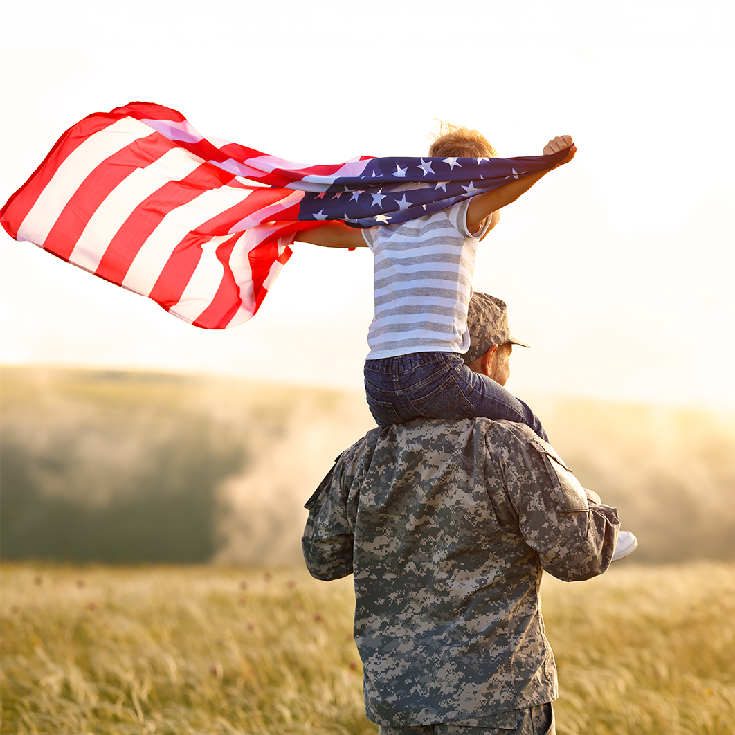 Soldier with son on his shoulders holding an American flag