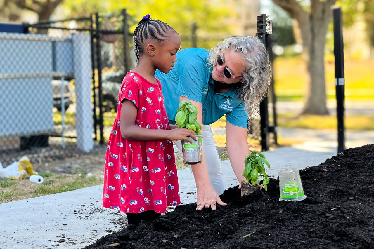 Ginsburg photo of Nancy Molello and a child planting basil