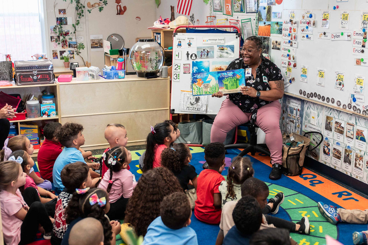 Ms. Crystal from the Orange County Library System leads an engaging read-aloud with early learners, fostering a love of books and storytelling.)